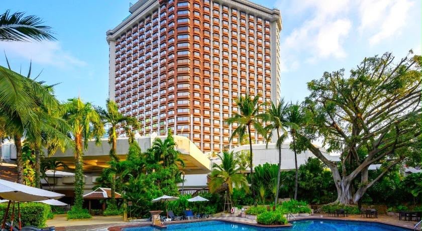 Tropikal bahçe ve havuzun ardında yükselen otel binası